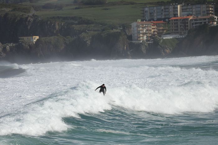 Surfer catching powerful waves on the scenic Basque coastline, blending sport and breathtaking views.