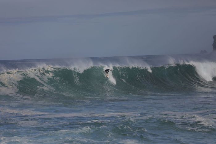 A surfer rides an enormous wave, showcasing the thrill of surfing in rough seas.