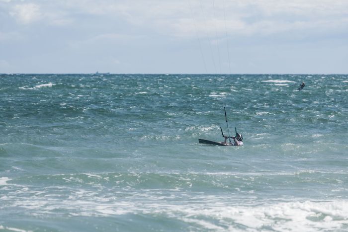 Kitesurfer navigating ocean waves under a bright sky, showcasing adventure and excitement.