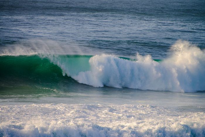 A mesmerizing view of a powerful wave crashing along the coast in Cascais, Portugal.