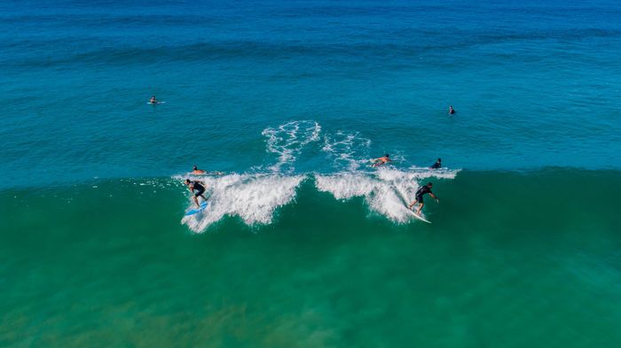 Surfers expertly riding waves in Rio de Janeiro, captured in a vivid aerial view.
