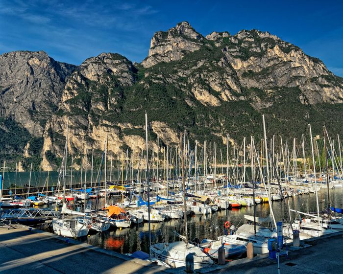Captivating view of a marina filled with sailboats, set against Italy's stunning mountains.