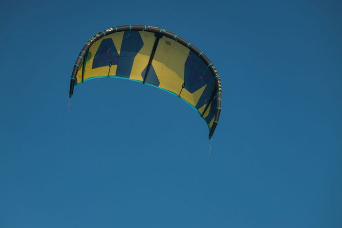Colorful kitesurf sail in vibrant flight against clear blue sky in Denmark, capturing the essence of wind sports.