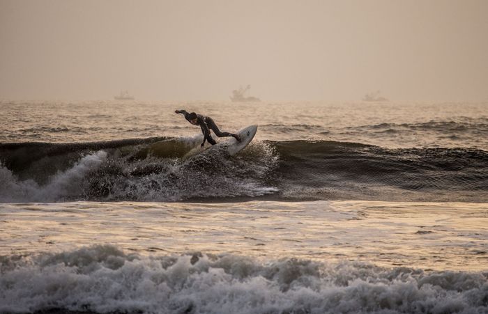 Silhouette of a surfer gracefully navigating waves during sunset at Pimentel Beach, Peru.