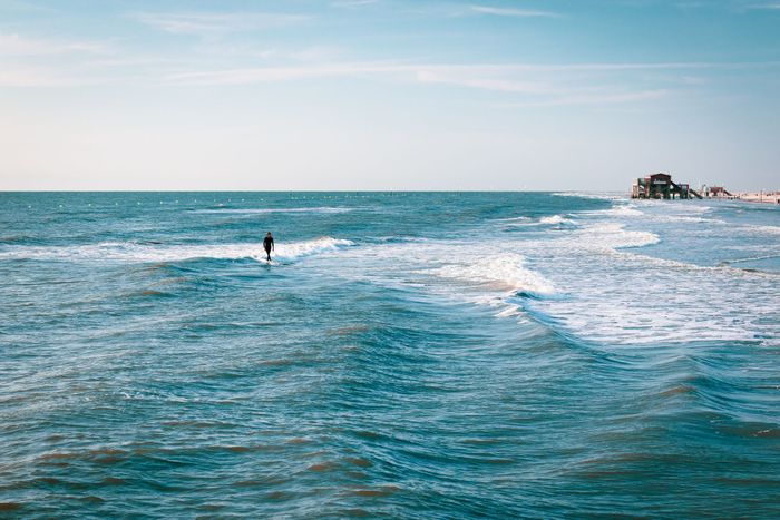 A surfer enjoying the summer waves at Sankt Peter-Ording beach in Germany.