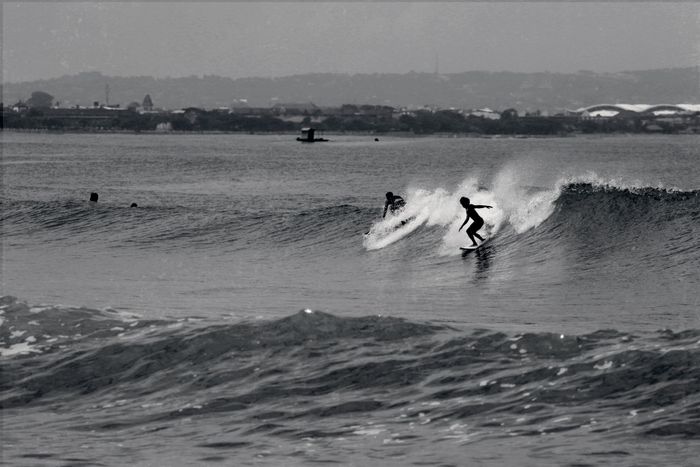 Black and white photo of surfers catching waves in Bali, Indonesia.