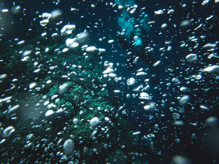 Scuba diver submerged, surrounded by air bubbles underwater, exploring ocean depths.