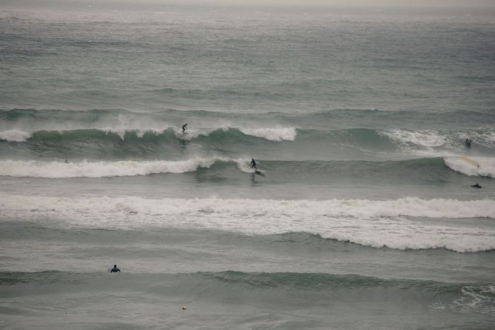 Surfers enjoying the waves on a cloudy ocean day, engaging in water sports.