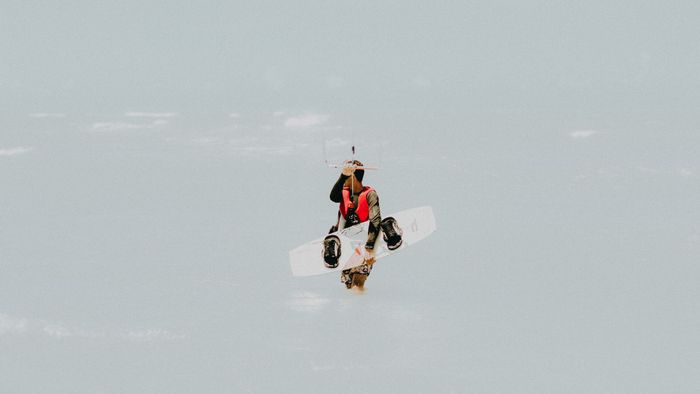 A kitesurfer holding equipment wades through the sea in Canoa Quebrada, Brazil.