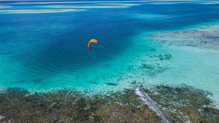 Aerial view of a kite surfer gliding over vibrant turquoise waters in Venezuela.
