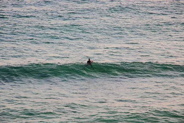 A lone surfer waits amidst the ocean waves, envisioning the perfect surf opportunity.
