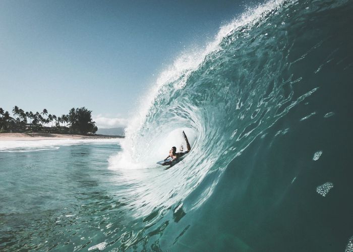 Exciting image of a surfer catching a massive wave on a picturesque Hawaiian beach.