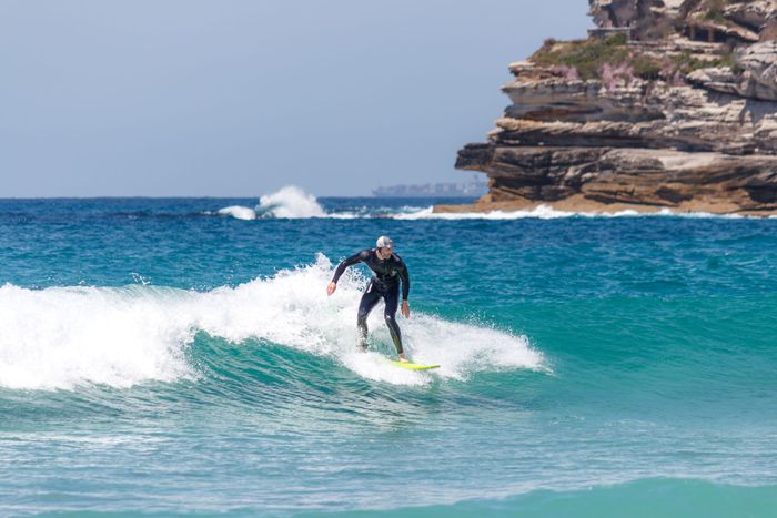 Surfer riding the waves at a scenic beach in New South Wales, Australia.