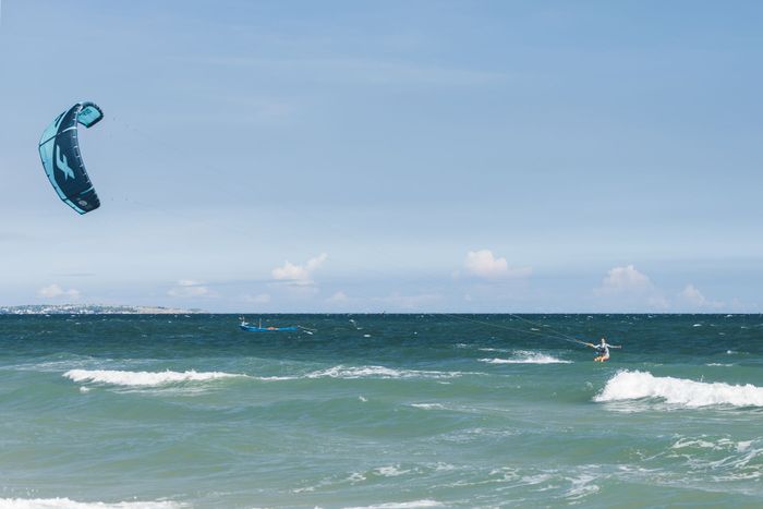 Exciting kitesurfing experience on ocean with clear skies and rolling waves.