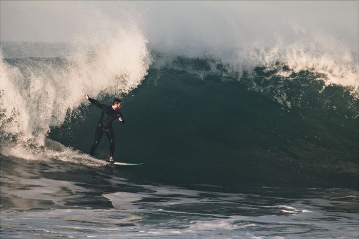 A dynamic shot of a surfer skillfully maneuvering a towering ocean wave, capturing pure adrenaline.