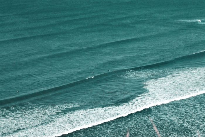 Aerial view of surfers riding waves at Sopelana beach, Spain. Perfect for travel or nature themes.