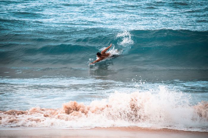 An adventurous surfer catches waves at a Hawaiian beach under the bright sun