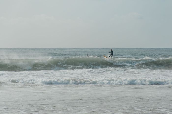 A lone surfer skillfully rides a wave in the open ocean on a sunny day.