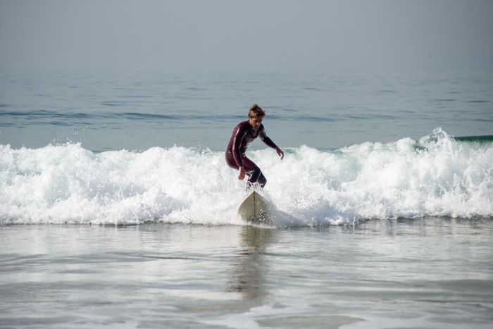 Surfer rides the vibrant waves of Portugal's coastline, capturing the essence of water sports.