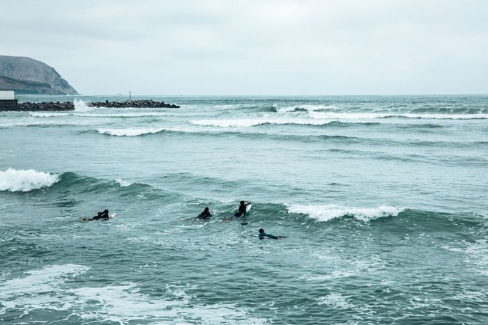 Group of surfers navigating waves off the coast of Lima, Peru, showcasing the vibrant surfing culture.