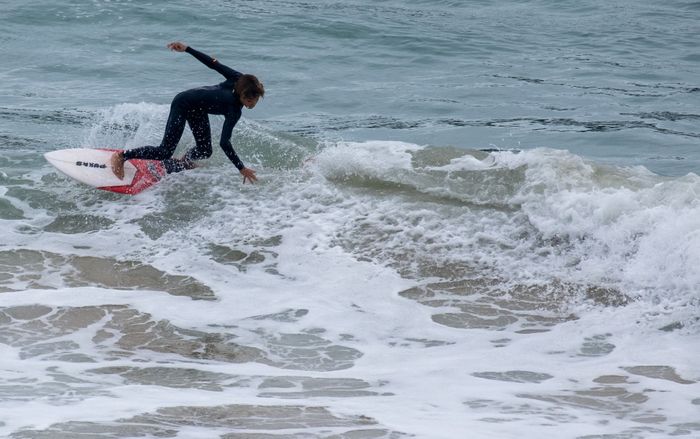 Surfer catches a wave, showcasing skill and agility in the ocean's surf.
