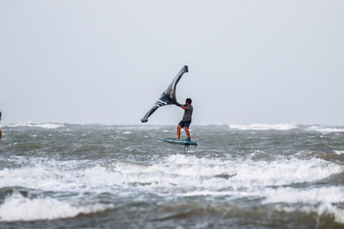 A thrilling capture of a man wing foiling over ocean waves, showcasing adventure and skill.