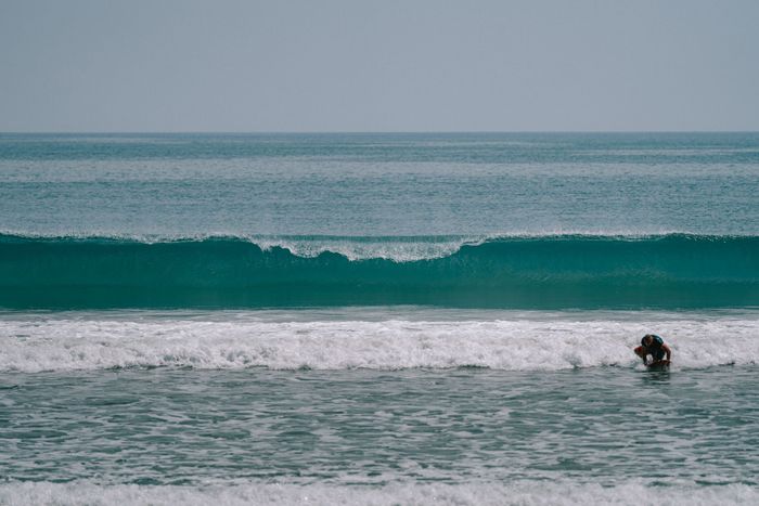 A surfer enjoys the waves at Kuta Beach in Bali, Indonesia, a popular surfing destination.