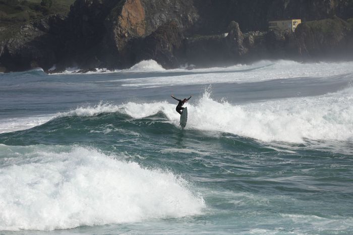 A surfer skillfully rides the waves on a rugged coastal beach, capturing the essence of surf culture.