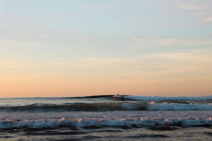 A surfer rides the waves at sunset on the Basque coast, capturing the tranquil ocean beauty.