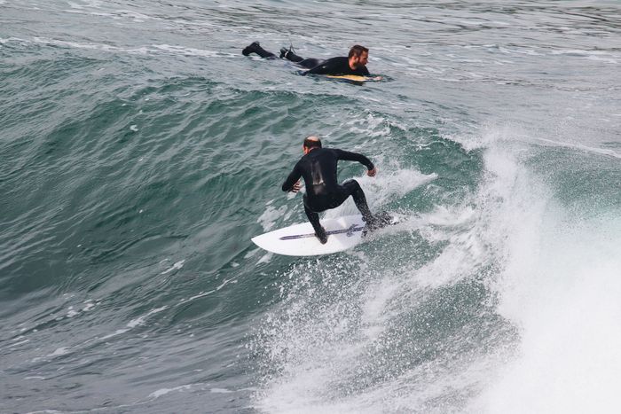 Two surfers riding impressive ocean waves, capturing the thrilling essence of the sport.