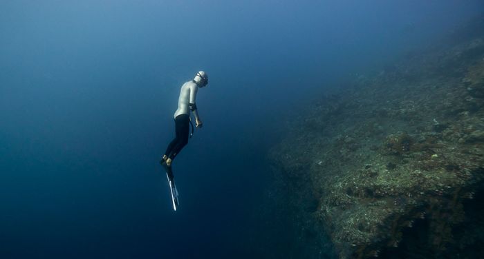 A scuba diver explores the depths of a coral reef in Bali, capturing the underwater beauty.