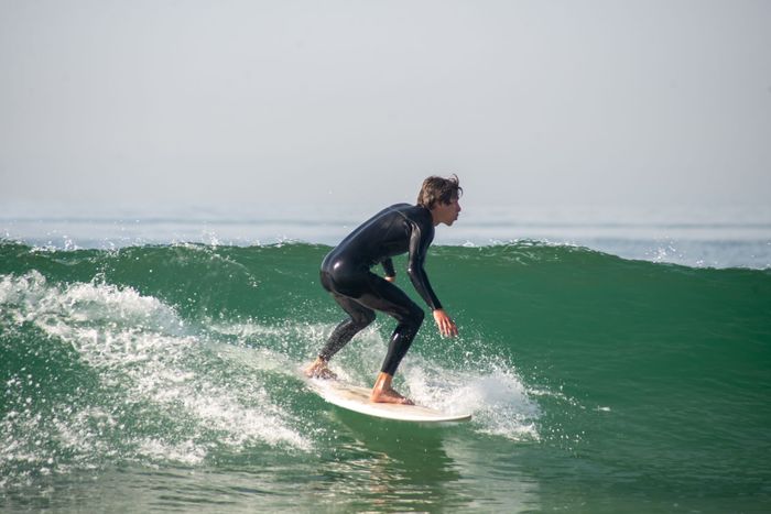 A young surfer skillfully rides waves in Portugal, showcasing surfing skills.
