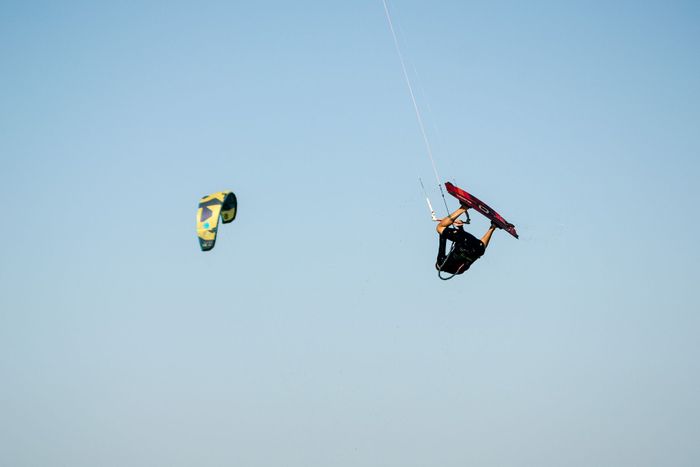 A skilled kitesurfer executing a stunning aerial maneuver against a clear blue sky in Argentina.