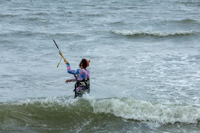 A kitesurfer enjoys an adventurous ride in the ocean waves, showcasing kitesurfing skill.