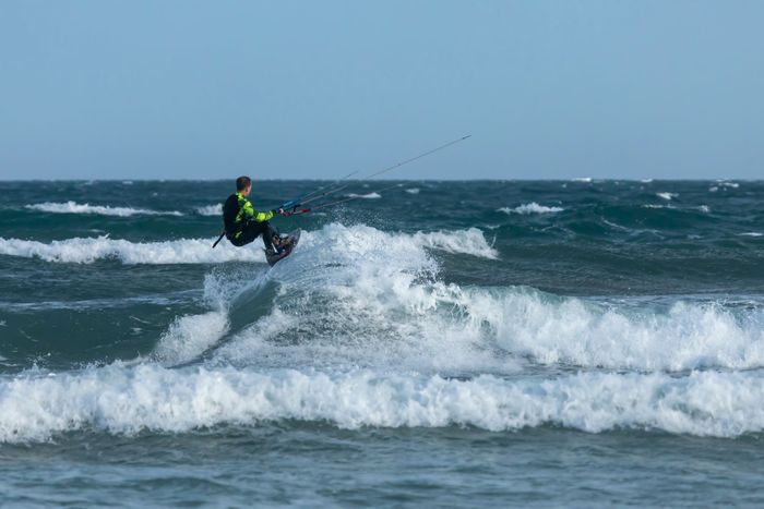 An exhilarating kitesurfer rides the ocean waves, showcasing skill and adventure.