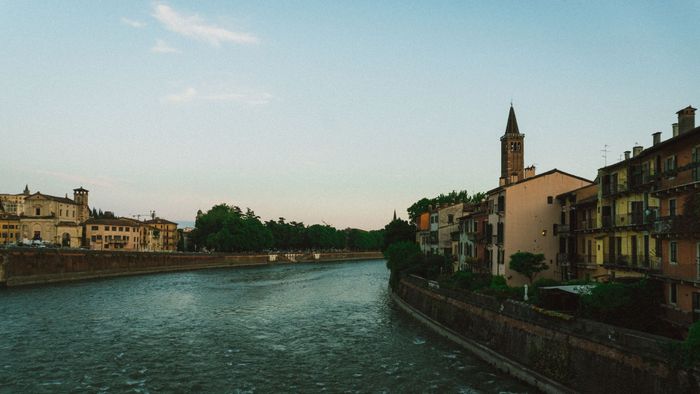 A picturesque view of historic buildings along the river in Verona, Italy during sunset.
