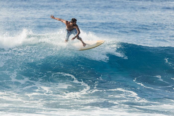 Dynamic shot of a surfer catching a wave in the crystal blue waters of the Maldives.