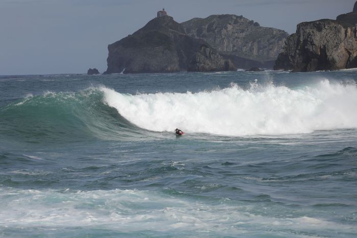 Surfer riding a massive wave on the coast of Bakio, capturing the thrilling surfing lifestyle.