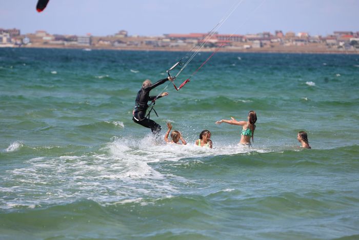 A group of young individuals enjoy an exhilarating kitesurfing adventure in the ocean waves.