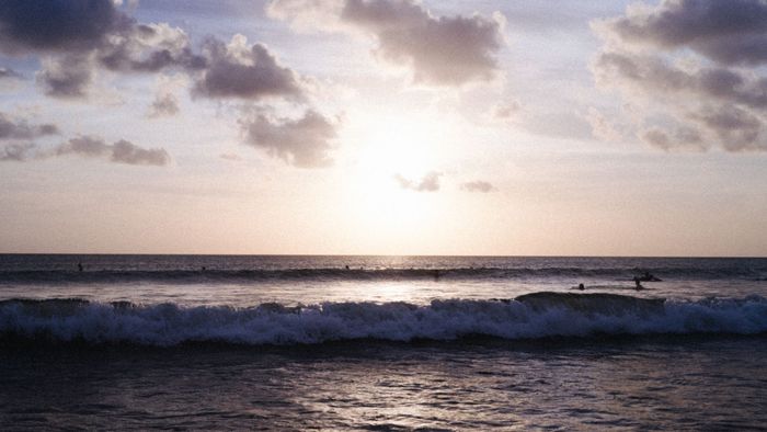 Enjoy a stunning sunset over the waves at Kuta Beach, Bali, perfect for surfing and relaxation.