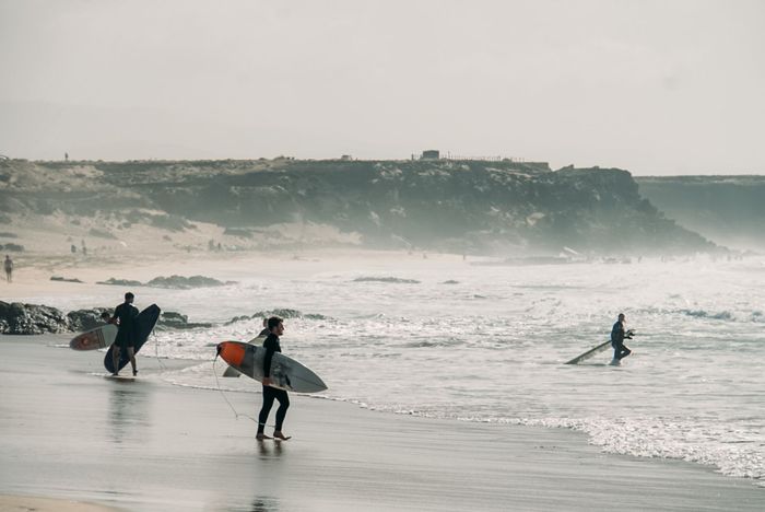 Surfers enjoy the waves at El Cotillo beach, a popular windsurfing spot in Spain.