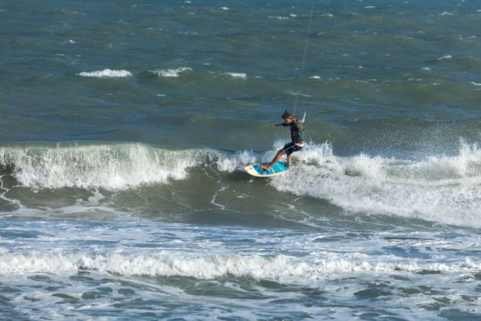 Man skillfully kitesurfing on rough ocean waves, capturing the thrill of adventure and water sports.