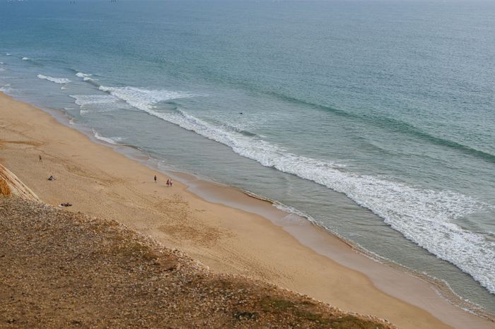 Drone shot capturing the serene coastline of Faro Beach, Portugal.