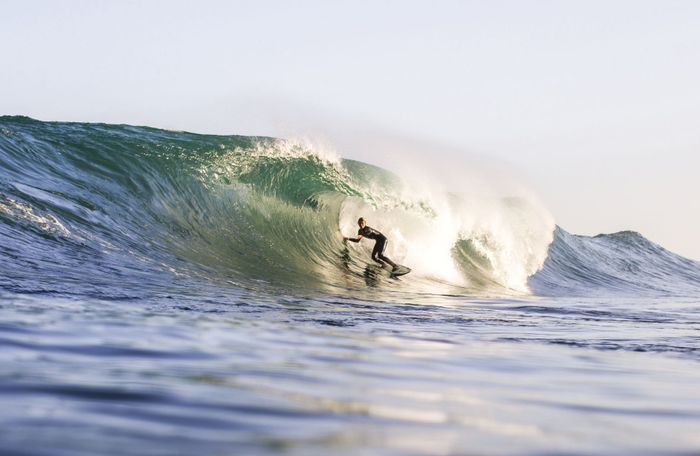 A surfer skillfully maneuvers a wave in California's ocean during daytime.