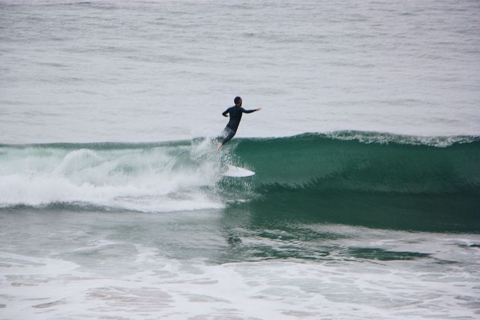 Surfer catches a wave, skillfully balancing on a surfboard amidst ocean waves.