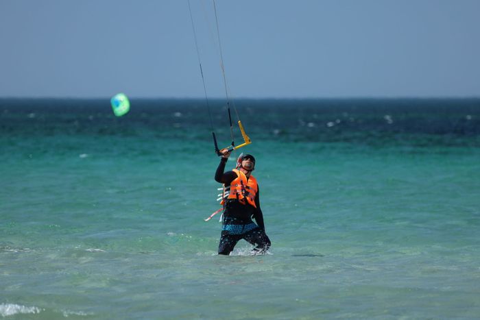 Kitesurfer enjoying an adventurous ride on the ocean with vibrant blue waters.
