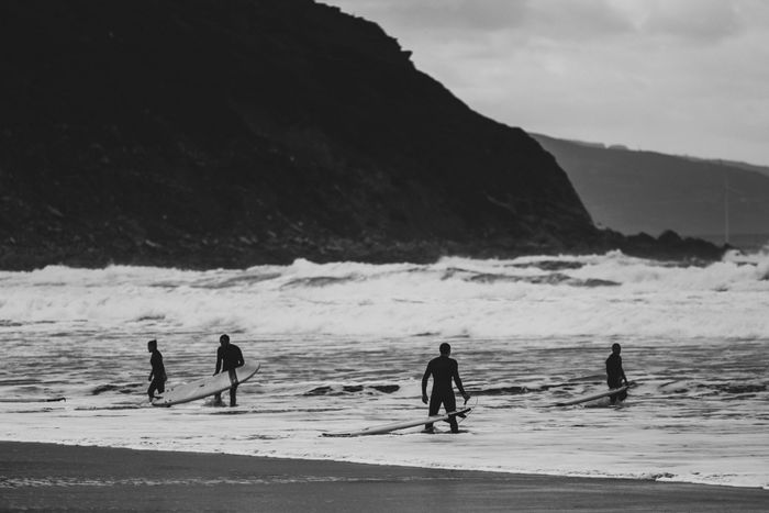 Black and white photo of surfers heading into the ocean at Bilbao beach, Spain.