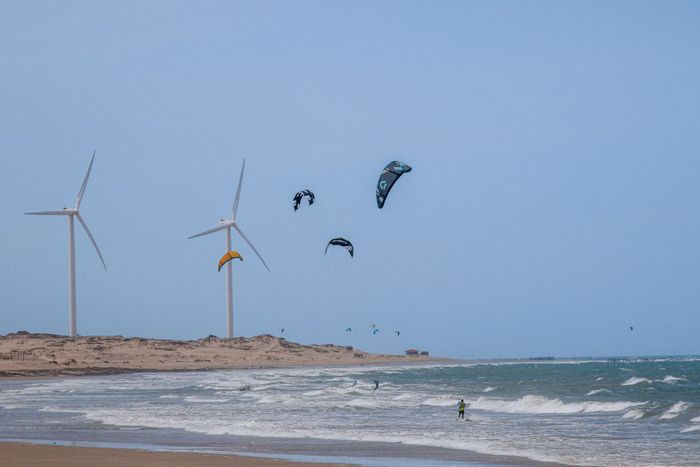 Kitesurfers enjoy the ocean with wind turbines in Icaraí, Brazil.