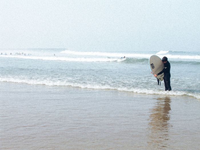 A surfer prepares to ride the Atlantic waves at Espinho Beach, Portugal.