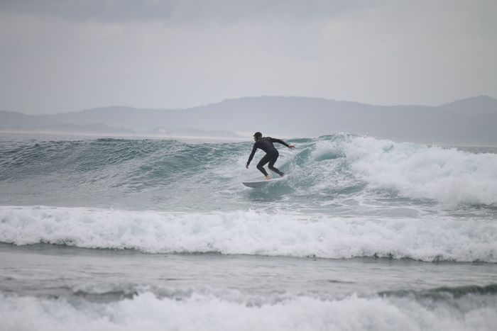 A surfer skillfully gliding on waves at Crescent Head, NSW, Australia.